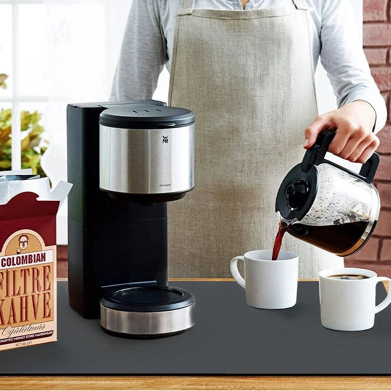 Personne se servant de Machine à café sur tapis absorbant noir 